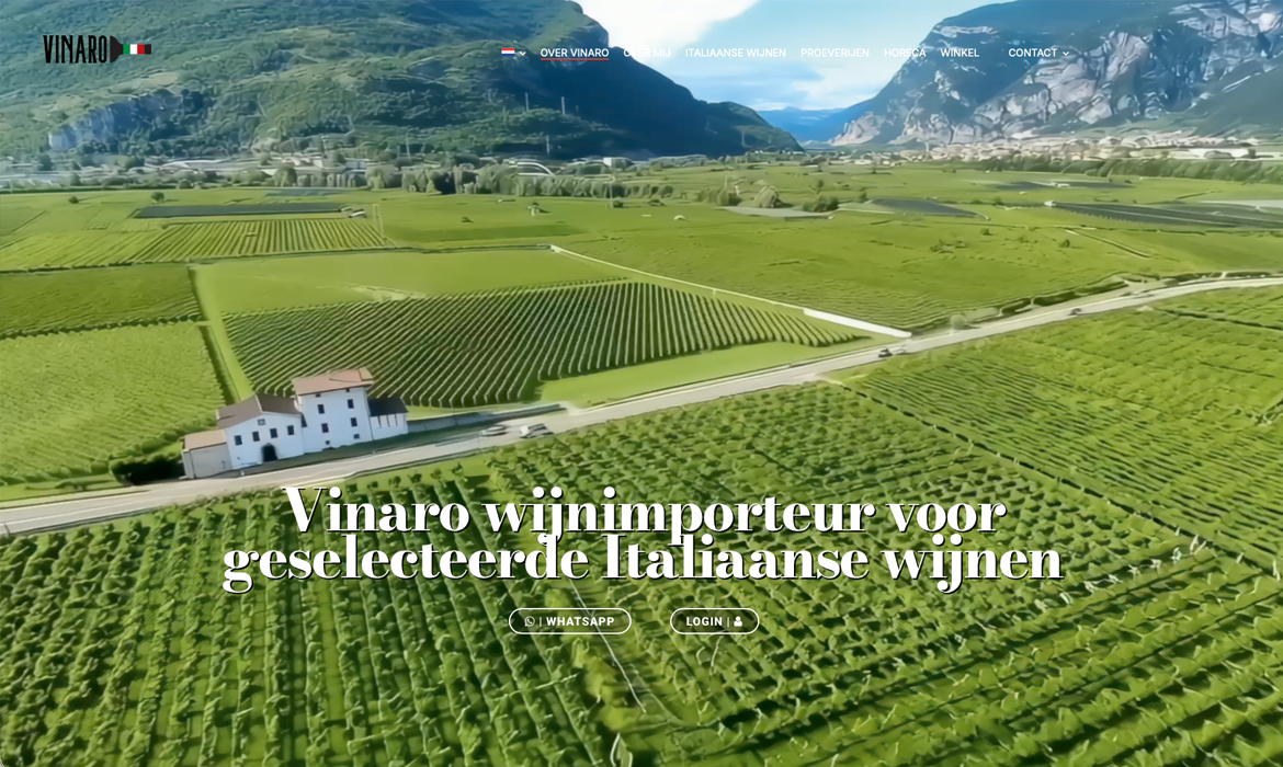 Vinaro cover - LeTigre Webdesign Holland Aerial view of lush vineyards with a white building, road, and mountains in the background, overlaid with Dutch hero text about Vinaro importing selected Italian wines.