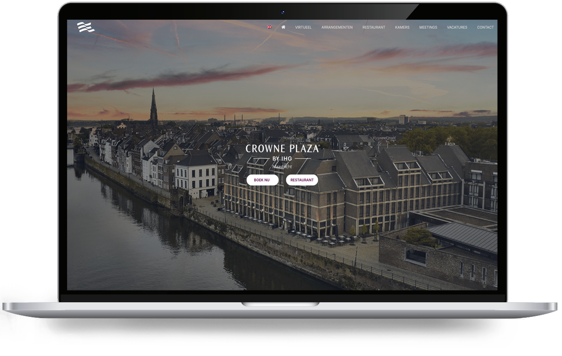 Crowne Plaza par Webdesign Holland - LeTigre Webdesign Holland Écran d'ordinateur portable affichant l'image phare du Crowne Plaza Maastricht : une ville au bord d'un fleuve au coucher du soleil, avec une barre de navigation et deux appels à l'action « Réservez dès maintenant » et « Restaurant »